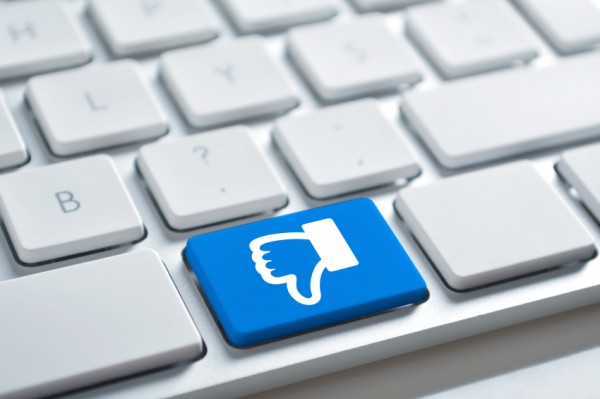 Blue thumbs-down key on a white keyboard, symbolizing dislike or negative feedback online.