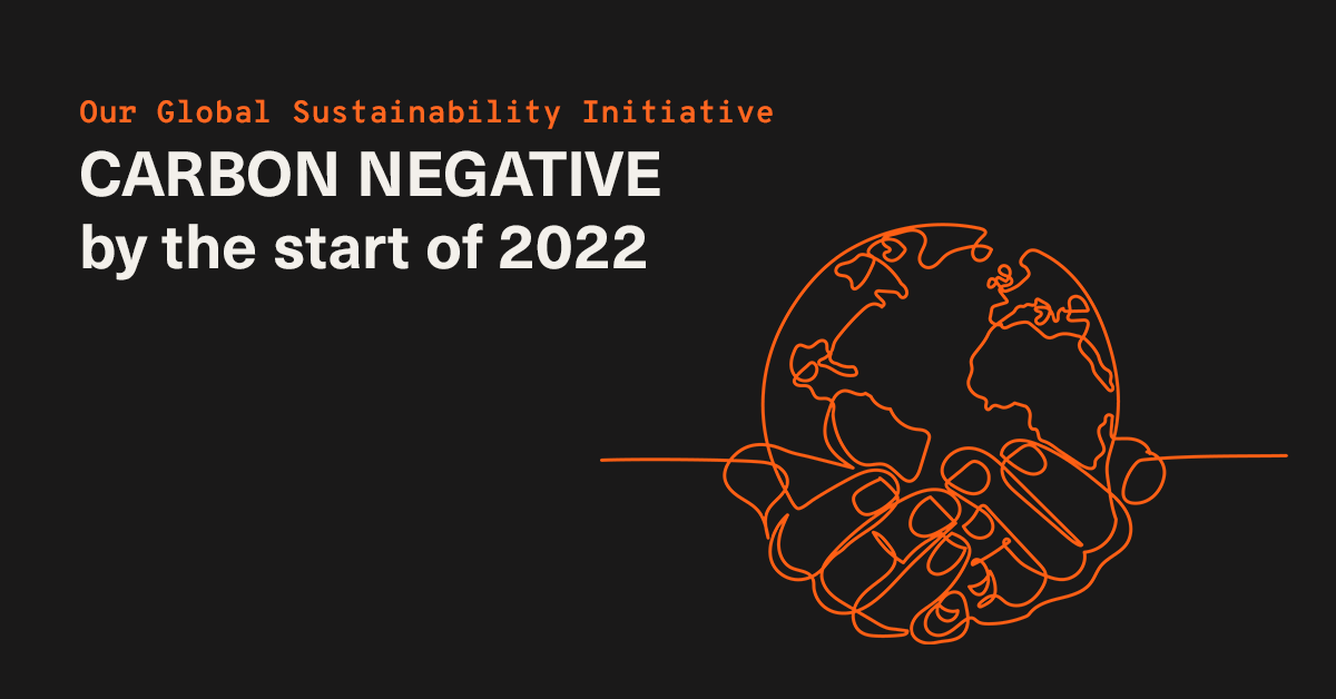 Our Global Sustainability Initiative: Carbon Negative by the start of 2022. An orange line drawing shows hands around a globe on a dark background.