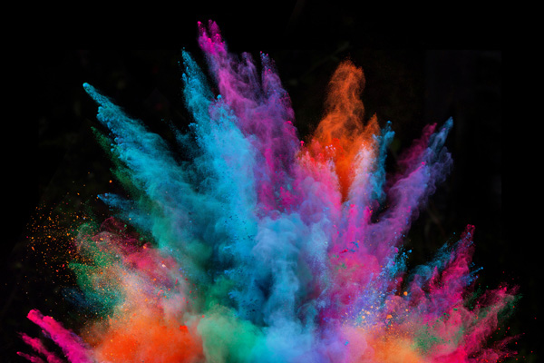 Vibrant colored powder bursts outward against a black background in a dynamic explosion effect (blue, pink, orange, green).