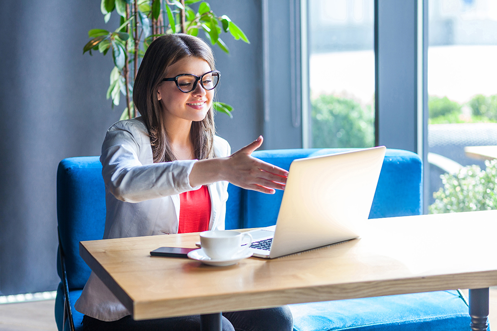 Person offering handshake to laptop