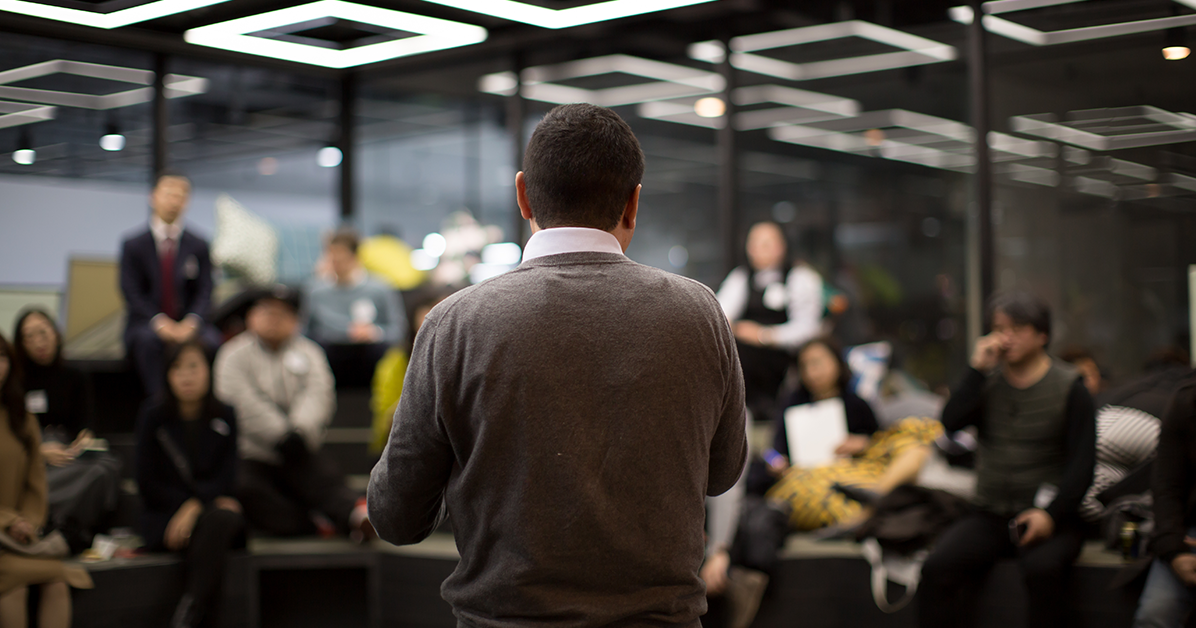 Man standing in front of a crowd presenting