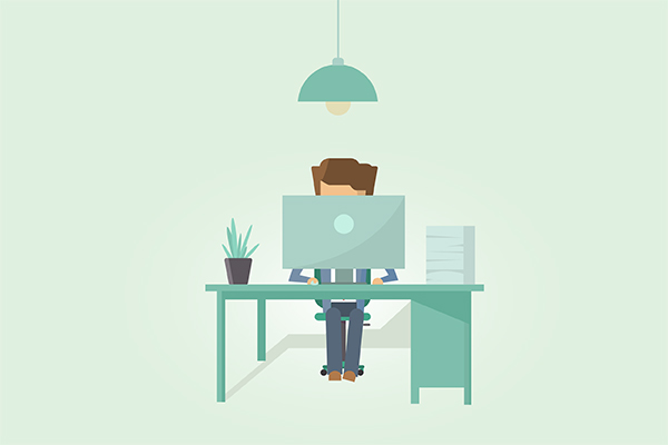 Person at a desk under a hanging lamp, working on a computer with a plant and a stack of papers on the desk.