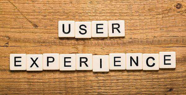 Tiles spell 'USER' above 'EXPERIENCE' on a wooden table, illustrating the concept of user experience (UX).